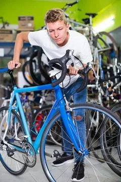 Portrait of interested male standing near the bicycle in the shop Stock Photos