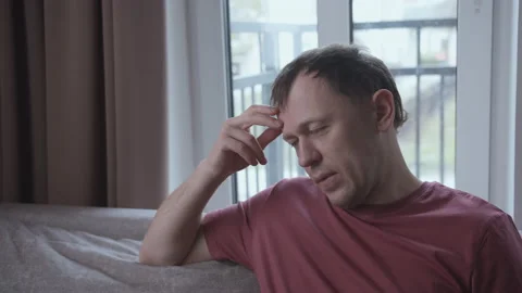Portrait of irritated man on sofa, window background Stock Footage 154559932