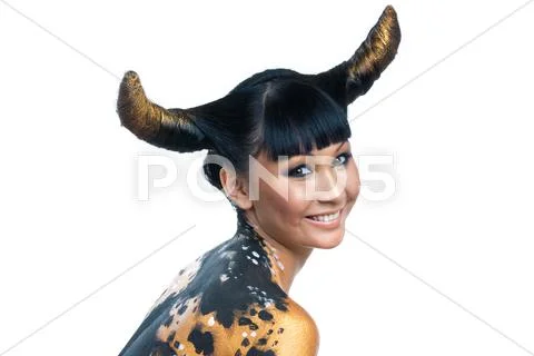 Portrait of joyful female with golden makeup and horns on head looking at camera Stock Photos
