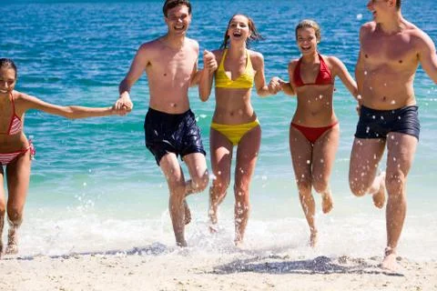 Portrait of joyful group of teens having fun on seashore and laughing Stock Photos