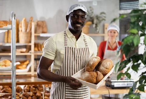 Portrait of joyful man baker with bread Stock Photos