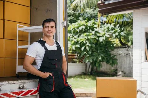 Portrait of a joyful mover working unloading boxes from a truck into a new home Stock Photos