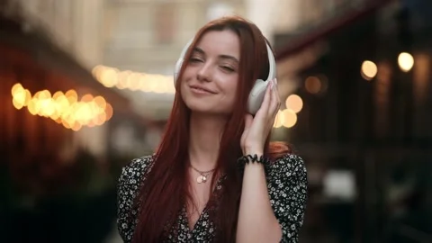 Portrait of joyful young red-haired woman listening to music in headphones Stock Footage 157923022