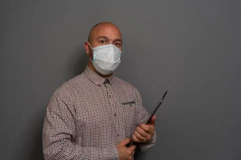 Portrait of a keep working bearded man with tablet in hands in a gauze mask P Stock Photos