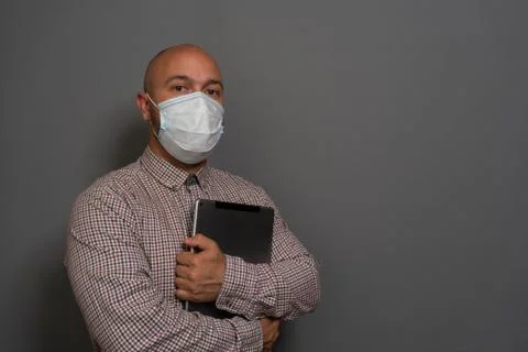 Portrait of a keep working bearded man with tablet in hands in a gauze mask P Stock-Fotos