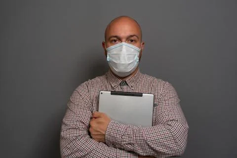 Portrait of a keep working bearded man with tablet in hands in a gauze mask P Stock Photos