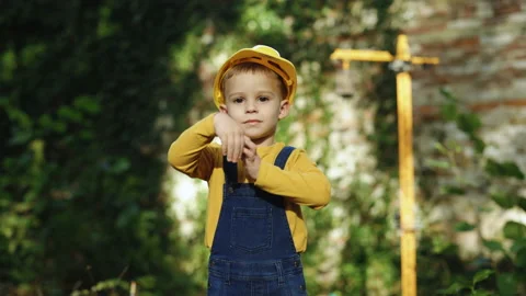 Portrait of kid boy builder wearing protective yellow helmet looking at camera Video stock 229735292