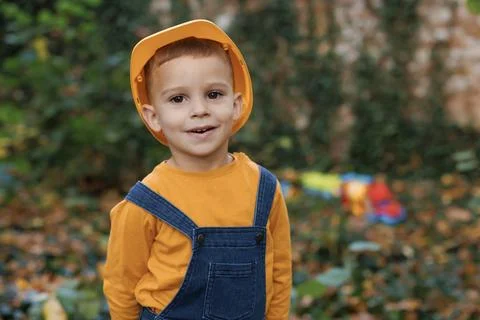 Portrait of kid boy builder wearing protective yellow helmet looking at camera Stock Photos