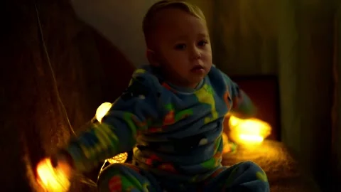 Portrait kid boy playing with christmas  garland in the evening.Magic vibe of ne Stock Footage 221360122