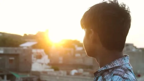 Portrait of a kid in front of the sun during the sunset Stock Footage 135812851