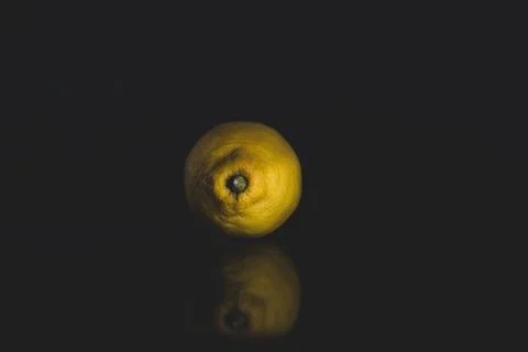 Portrait of a lemon on a black background with reflection and copy space Stock Photos