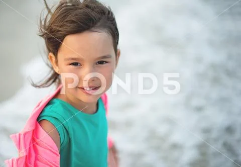 Portrait of little and beautifull girl smilling and having fun in the sea wav Stock Photos
