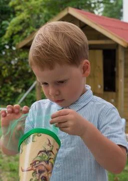 Portrait of a little boy. Opens a candy cone with interest. Foto stock