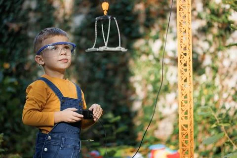 Portrait of little boy with remote control crane beam in an industrial warehouse Stock Photos