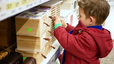 Portrait of a little boy in the store. The kid opens a wooden box looks into it. Stock Footage 153461236