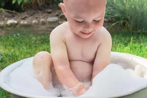 Portrait of a little boy taking a bubble bath in the summer outdoors Stock Photos