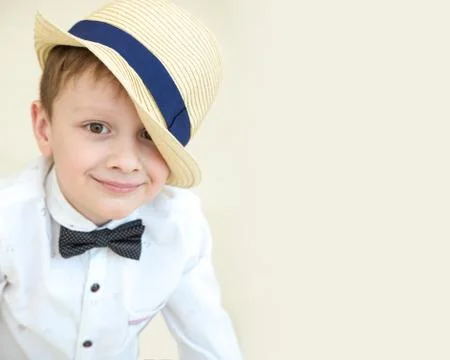 Portrait of a little boy in a white shirt and hat. He is smiling. On a beige Stock Photos