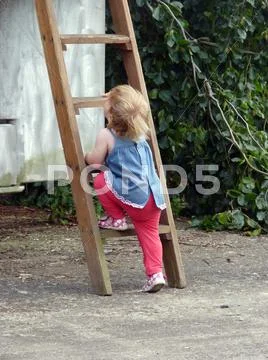 Portrait of little cute blond girl on the wooden staircase Stock Photos