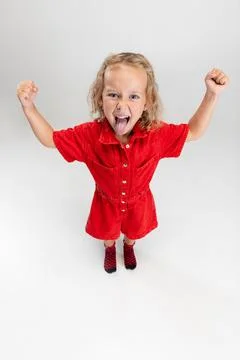 Portrait of little cute blonde preschool girl in red romper posing isolated over Stock Photos