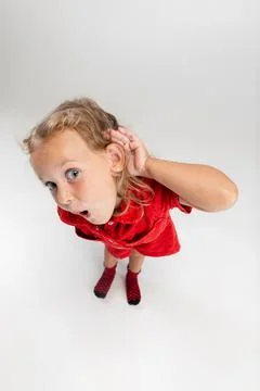 Portrait of little cute blonde preschool girl in red romper posing with her hand Stock Photos