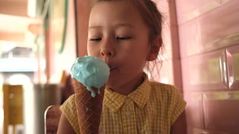 Portrait little girl eats cold ice cream in a cafe, summer, holidays Stock Footage 247271368