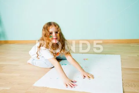 Portrait of little girl painting on a floor with her hands Stock Photos