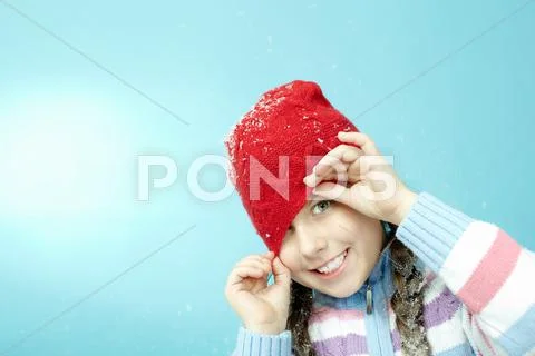 Portrait of little girl in woolen hat winking at camera Stock Photos