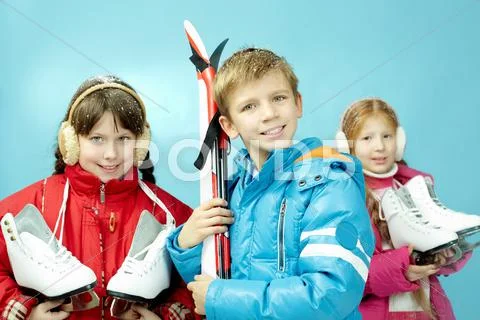 Portrait of little girls with skates and a boy with skis isolated on blue Stock Photos