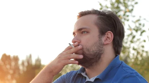 Portrait of a lonely man smoking a cigarette in sunlight Vidéo 65504953