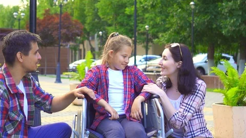 Portrait of looking at the camera mom and dad with a little daughter disabled in Stock Footage 92531804