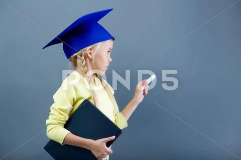 Portrait of lovely girl in graduation hat writing with chalk Stock Photos