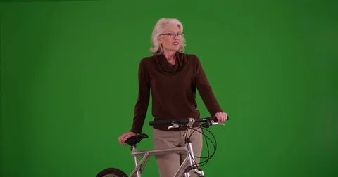 Portrait of lovely senior woman standing with bicycle on green screen Stock Footage
