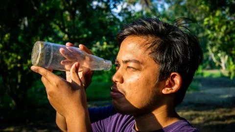 Portrait of Malay man seeing inside a glass bottle which act as binocular. Stock Photos
