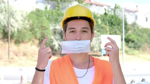 Portrait of male engineer or worker with yellow helmet wearing facemask smilling Stock Footage 136923215