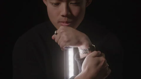 Portrait of Male Model Looking Down Holding Bright Light in Studio Video stock 270304248