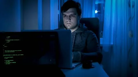 Portrait of male programmer or hacker working on computer at night Stock-Fotos