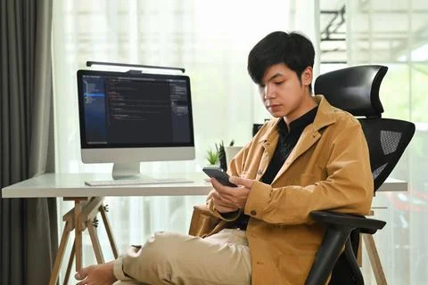 Portrait of male programmer sitting in front of computer monitor with Stock Photos