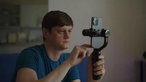 Portrait of male videographer using smartphone mounted on gimbal stabilizer Stock Footage 342809786