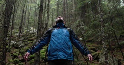 Portrait of a man with a backpack standing in the rain in the forest Stock Footage 243597757