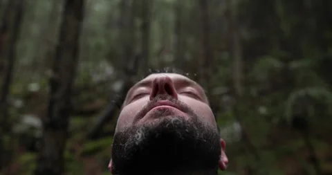 Portrait of a man with a backpack standing in the rain in the forest Stock Footage 243597876
