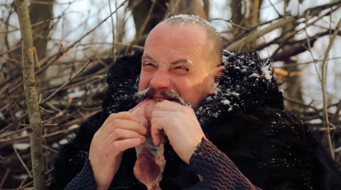 Portrait of a man with a beard devouring raw meat. Vidéo 59754289