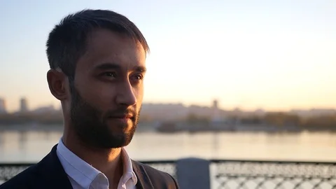 Portrait of a man with a beard in a jacket against the background of the river Stock Footage 117426908