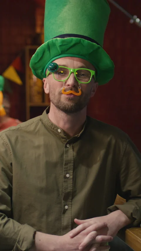 Portrait of Man in Big Green Hat and Funny Glasses Posing in Irish Pub Stock Footage 262980063