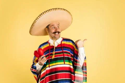 Portrait of man in bright garment and sombrero isolated over yellow background Stock Photos