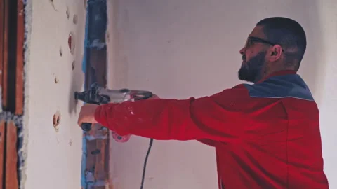 Portrait of man builder in workwear drilling wall with hammer drill Stock Footage 241070401