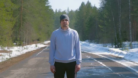 Portrait of man in cap in forest standing on country road and looking at camera. Stock Footage 129596456