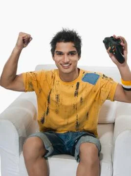 Portrait of a man cheering while playing video game Stock Photos