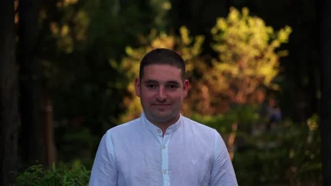 Portrait of a man close-up on a background of trees in the park. Video stock 139592914