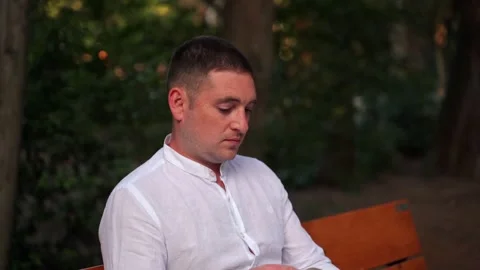 Portrait of a man close-up on a background of trees in the park. A man in a park Stock Footage 139593272