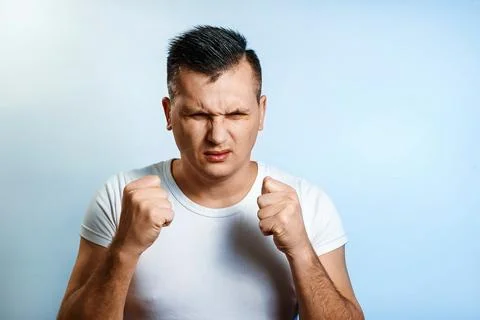 Portrait of a man close-up, experiencing anger, hate, against a light backgro Stock Photos